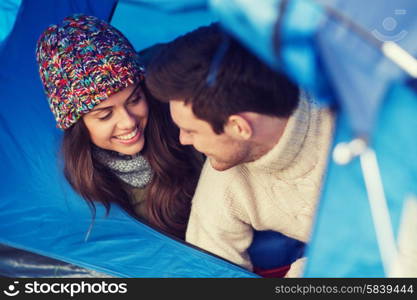 camping, travel, tourism, hike and people concept - smiling couple of tourists looking out from tent