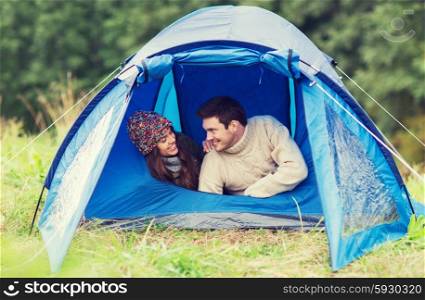 camping, travel, tourism, hike and people concept - smiling couple of tourists talking in tent