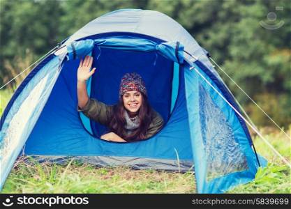 camping, travel, tourism, hike and people concept - smiling female tourist waving hand in tent