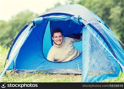 camping, travel, tourism, hike and people concept - smiling male tourist in tent