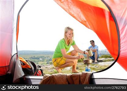 Camping young couple outside tent cook meal countryside view