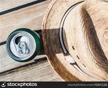 Can of beer and sunhat. Top view, close-up. Concept of leisure and travel. Can of beer on a beautiful background