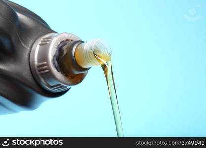 Can with car engine oil pouring in front blue background