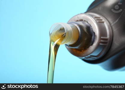 Can with car engine oil pouring in front blue background