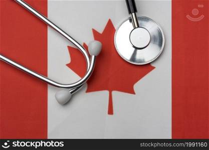 Canada flag and stethoscope. The concept of medicine. Stethoscope on the flag in the background.. Canada flag and stethoscope. The concept of medicine.