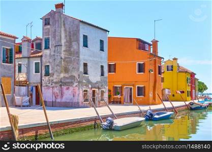 Canal with boats and colorful houses in Burano island on summer sunny day, Venice, Italy