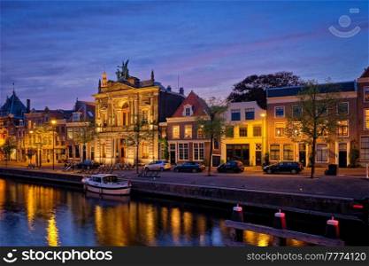 Canal with boats and houses illuminated in the evening. Haarlem, Netherlands. Canal and houses in the evening. Haarlem, Netherlands