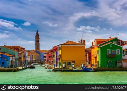 Canal with colorful houses, church, boats and bridge on the famous island Burano, view from the sea, Venice, Italy