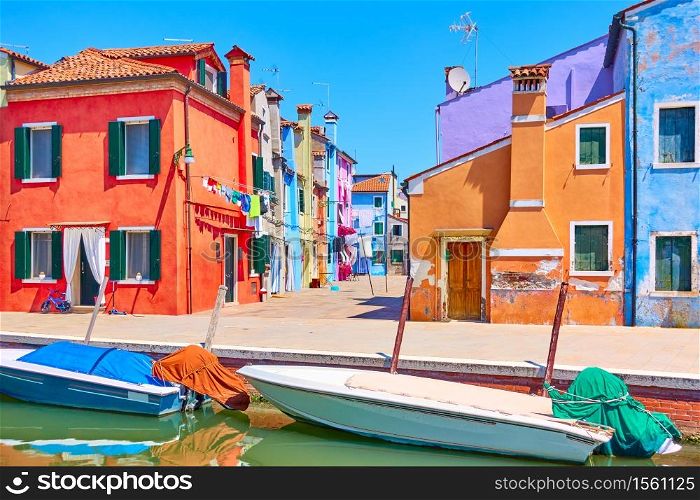 Canal with motorboats and colorful houses in Burano in Venice, Italy - Italian view