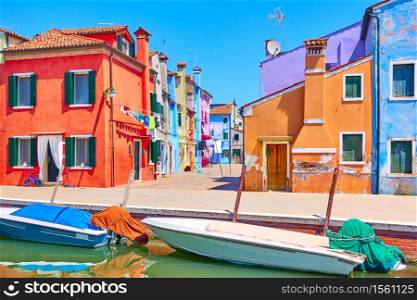 Canal with motorboats and colorful houses in Burano in Venice, Italy - Italian view