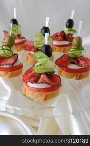 Canape of the baguette with salami on a glass base