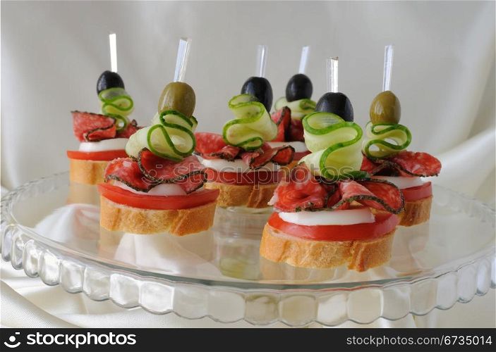 Canape of the baguette with salami on a glass base