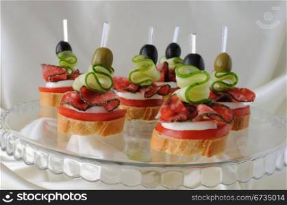 Canape of the baguette with salami on a glass base