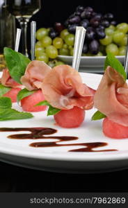 Canape of watermelon balls slice of gammon with basil