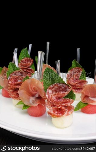 Canape of watermelon balls with a melon with gammon and salami