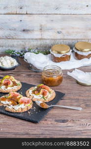 Canape or crostini with multigrain crispread with cream cheese and fig jam on a slate board. Delicious appetizer ideal as an aperitif.