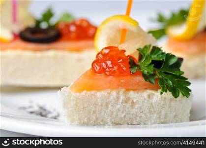 canape with red caviar and smoked salmon, served on plate. canape with red caviar and smoked salmon
