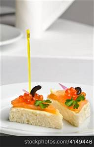 canape with red kaviar and smoked salmon, served on plate. canape with red kaviar and smoked salmon