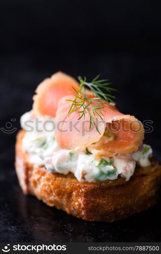 Canape with smoked wild salmon and cream cheese, dark background, selective focus, copy space