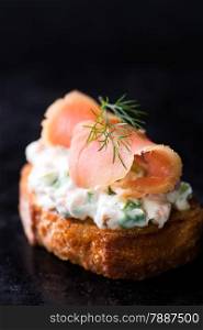 Canape with smoked wild salmon and cream cheese, dark background, selective focus, copy space