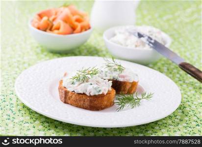 Canape with soft cheese spread on white plate, close up, selective focus