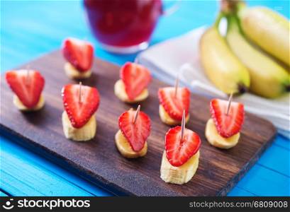 canape with strawberry and banana on wooden board