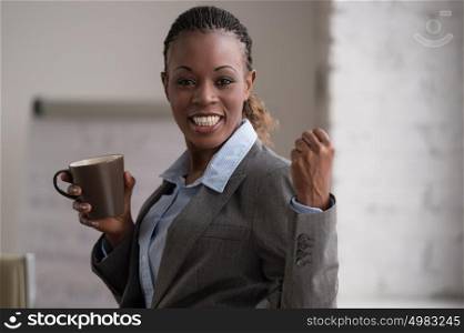 Candid image of a businesswoman drinking coffee while working at office. Selective focus.