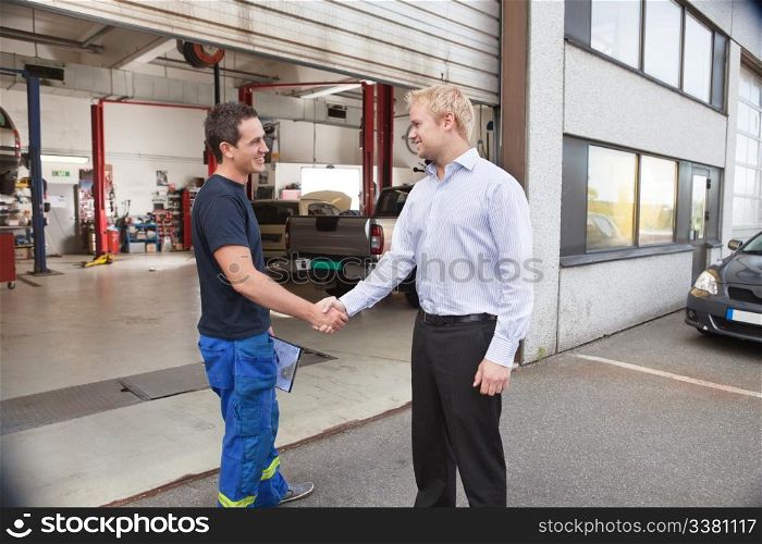 Candid portrait of a mechanic shaking hands with client