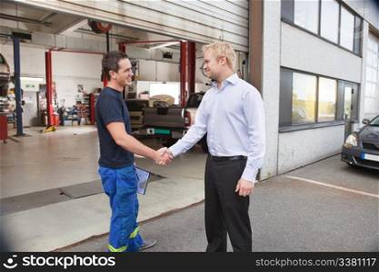 Candid portrait of a mechanic shaking hands with client