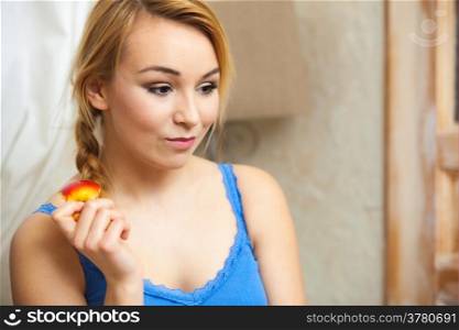 Candid portrait of pensive woman with apple. Teenage girl eating fresh fruit inddor. Healthy diet and nutrition.