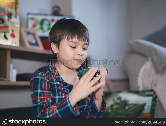 Candid shot Happy kid playing with plastic toy,Positive child playing alone in living room,Cute young boy relaxing at home on weekend,Children imagination and development