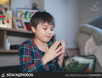 Candid shot Happy kid playing with plastic toy,Positive child playing alone in living room,Cute young boy relaxing at home on weekend,Children imagination and development