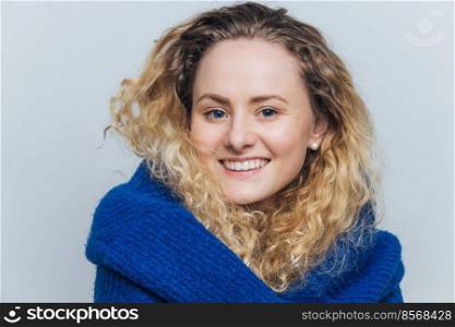 Candid shot of pleased attractive female has appealling appearance, healthy pure skin, has broad smile on face, being in good mood after date with boyfriend, isolated over light blue background
