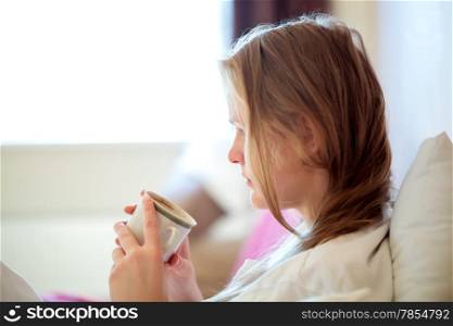 Candid side view portrait of a young blond woman drinking coffee sitting looking down at the mug in her hands, with copyspace