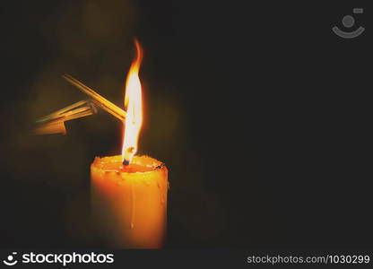 Candle burning at night. The light of the candle illuminates the darkness, Candlelight in the dark with focus on single candle in black background.