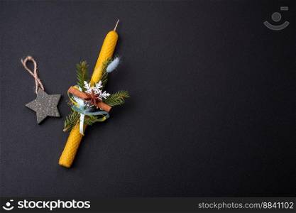Candle decorated with Christmas decorations on a dark concrete background. Holiday home decoration