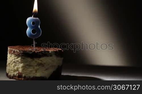 Candle eight in tiramisu cake. Birthday vintage background.