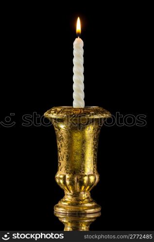 Candle in golden vintage candlestick isolated on black with reflection