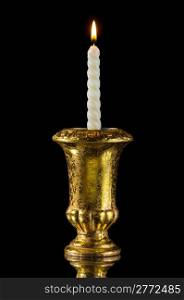 Candle in golden vintage candlestick isolated on black with reflection