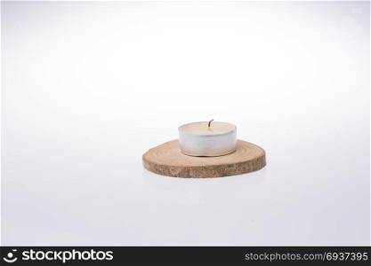 Candle placed on a piece of wood on a white background