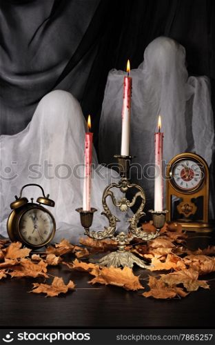 Candles among the fallen leaves with a clock and ghosts