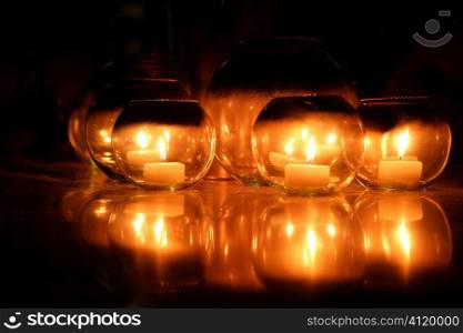 Candles in round glasses over black background