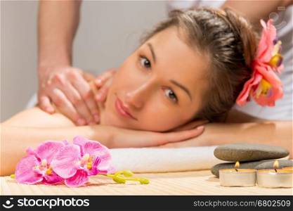 candles, stones and flowers for spa treatments and the girl's face out of focus