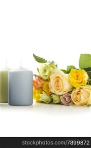 Candles with a bouquet of fresh colorful roses in tribute and remembrance of a departed loved one or as a symbol of love on an anniversary or Valentines Day, vertical on white with copyspace