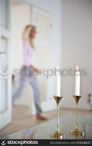 Candles. Woman passes through the living room which is illuminated by candle ligts.