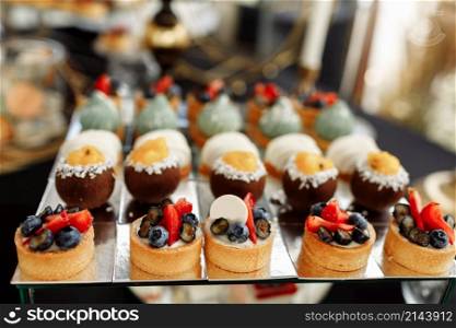 Candy bar on wedding party with a lot of different candies, cupcakes, souffle and cakes on mirror plate. Candy bar on wedding party with a lot of different candies, cupcakes, souffle and cakes on mirror plate.