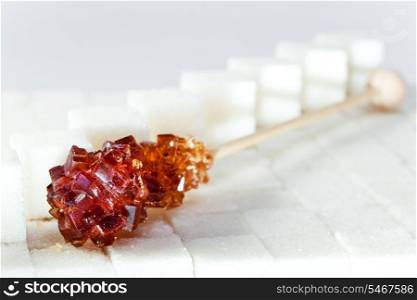 candy brown sugar on a stick lies on white lumpy sugar