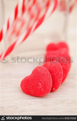 Candy canes and heart-shaped candies on a wooden grey background. Soft focus