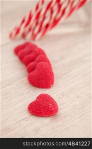 Candy canes and heart-shaped candies on a wooden grey background. Soft focus