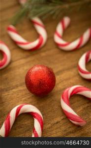 Candy canes with Christmas balls on a wooden background